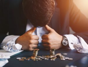dip financing recuperação judicial - homem frustrado com a cabeça encostada na mesa